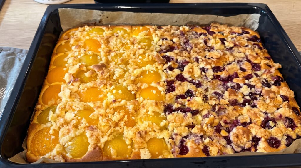 Cuca alemã original assada com metade pêssego e metade cereja em calda, streusel crocante por cima