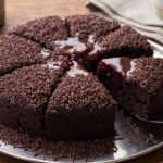 Bolo de chocolate fofinho com cobertura de ganache cortado ao meio mostrando a massa umida